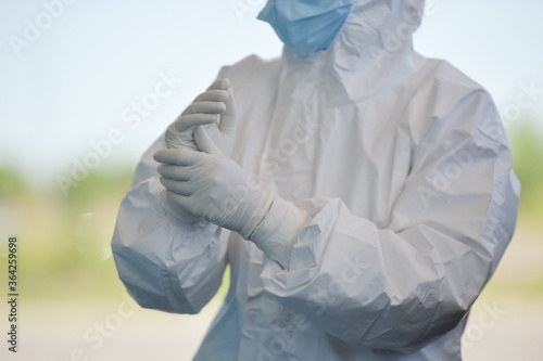 Unrecognizable people wearing protective suit handles a pharyngeal exudate/ swab collection kit for the coronavirus. Test tube for taking OP NP patient specimen sample, PCR DNA testing