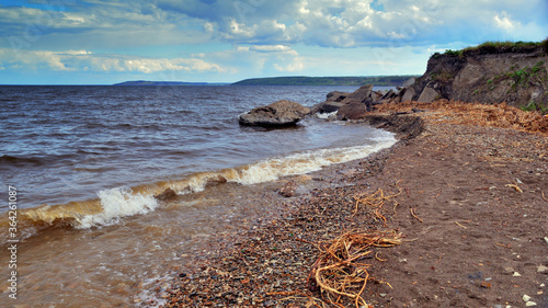 Algae and stones are on the beach and in the water. Beautiful riverside with small stones and sand after heavy rain.