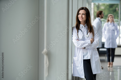 Portrait of young woman doctor with white coat standing in hospital.