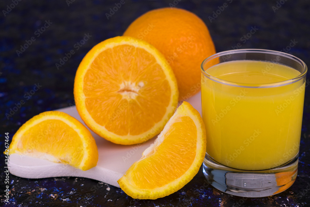 A glass of fresh orange juice on a dark blue background.
A glass of fresh orange juice on a dark blue background.