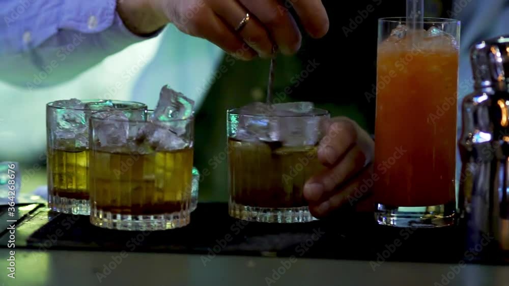 bartender pours a mixed drink at the bar. Drinking glasses closeup. bartender pours a mixed drink at the bar. Drinking glasses closeup.