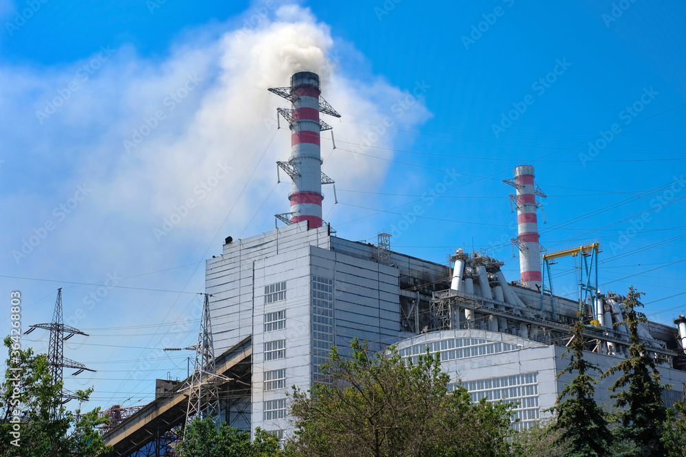 Obraz premium Thermal power plant, industrial chimney against a clear blue sky.