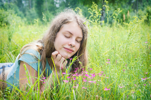In the summer  a girl lies in a flower meadow.