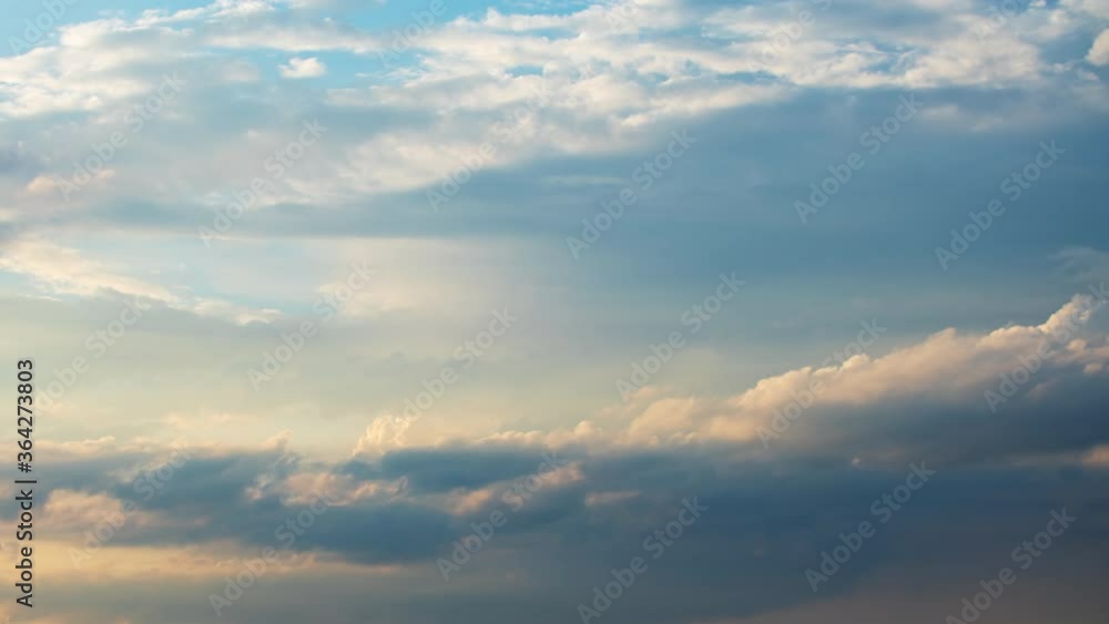 Moving white and yellow clouds shot in time-lapse. Idyllic cloudy heaven background. Timelapse of beautiful clouds in blue evening sky. Sunset, golden hour sunlight Moving white and yellow clouds shot in time-lapse. Idyllic cloudy heaven background. Timelapse of beautiful clouds in blue evening sky. Sunset, golden hour sunlight