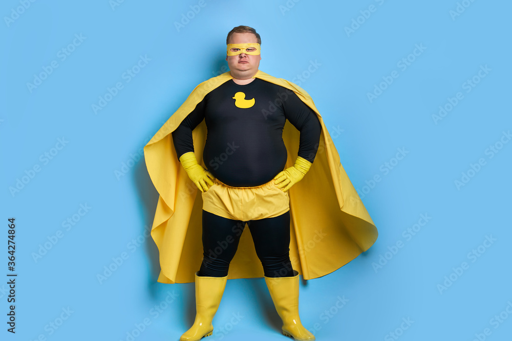 cleaning superhero saves the world from dirt, man has duck picture on  costume, he is in yellow wear and in protective gloves, posing isolated  over blue background Photos | Adobe Stock