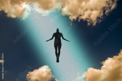 The dark silhouette of the soul of a deceased person ascends to heaven against a background of clouds. Afterlife, the concept of the immortality of the soul. 3D rendering
