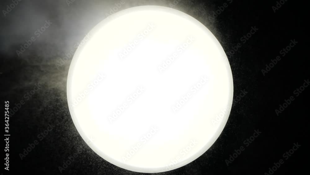 Strong smoke blows on a white ball against a dark background. Someone ...