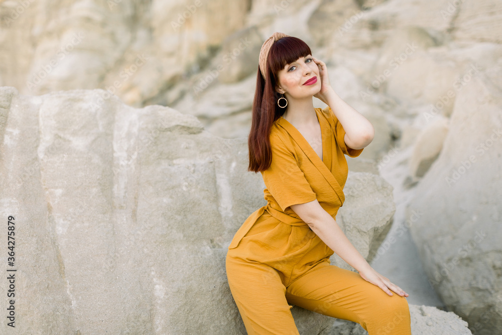 Half length horizontal portrait of charming female model in fashionable yellow overalls posing in sand quarry. Summer woman portrait in canyon. Copy space Half length horizontal portrait of charming female model in fashionable yellow overalls posing in sand quarry. Summer woman portrait in canyon. Copy space