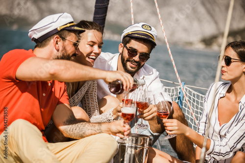 Smiling friends with glasses of champagne on yacht. Vacation, travel, sea, friendship and people concept