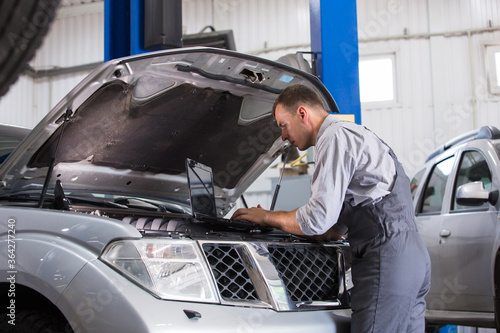 car service worker carries out diagnostics and car repairs in the room.