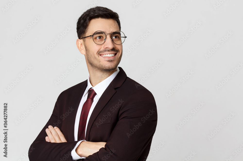 Young successful smiling businessman or CEO, cheif executive officer with crossed arms looking away, isolated on gray background - obrazy, fototapety, plakaty 
