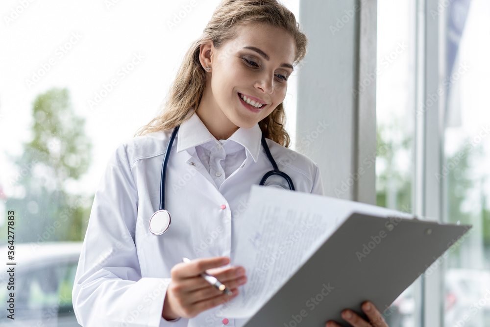 Woman doctor standing with folder at hospital. Woman doctor standing with folder at hospital.