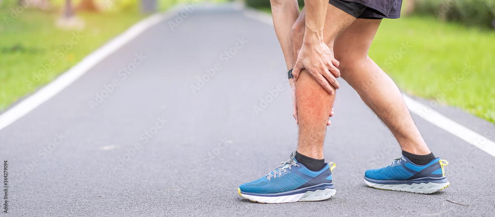 Young adult male with his muscle pain during running. runner man having leg ache due to Calf muscle pull. Sports injuries and medical concept