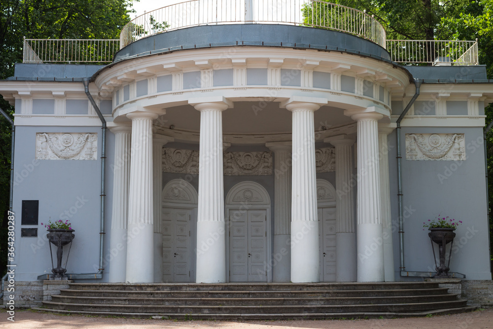 Fototapeta premium A pavilion standing in the Park, decorated with a rotunda with white columns, bas-reliefs and cast-iron vases .
