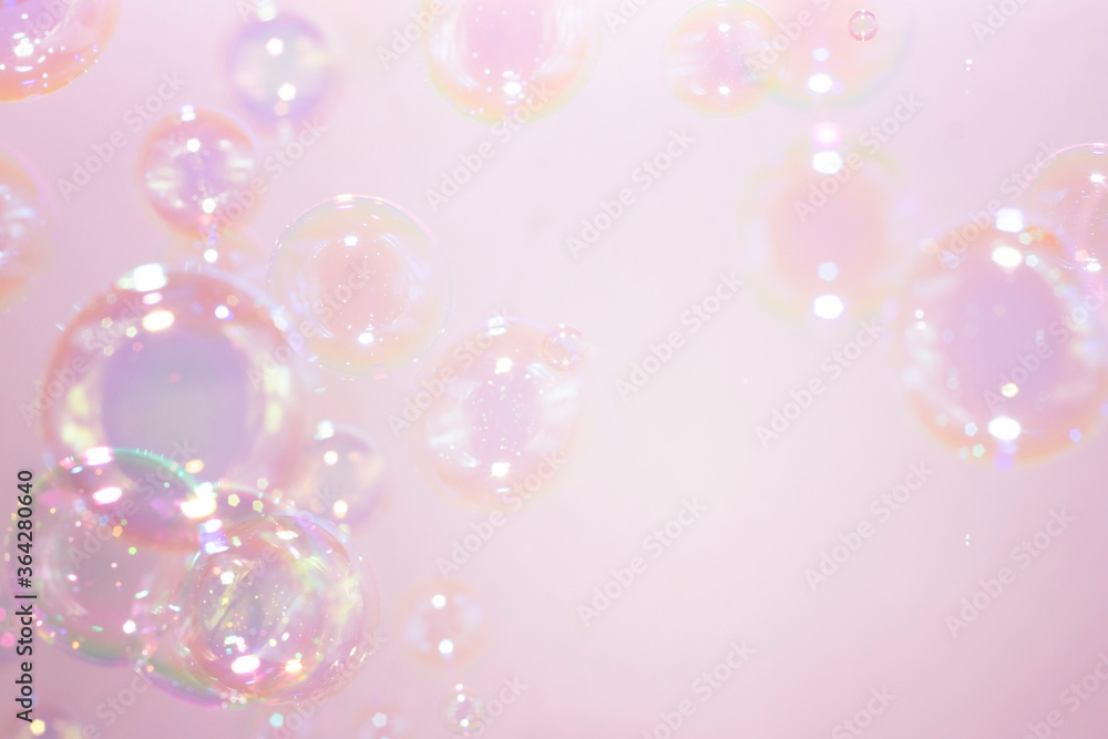 Beautiful rainbow soap bubbles float on pink background. Abstract bubble blur background.
