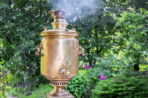 Fotografija A traditional Russian samovar is heated by wood in the garden