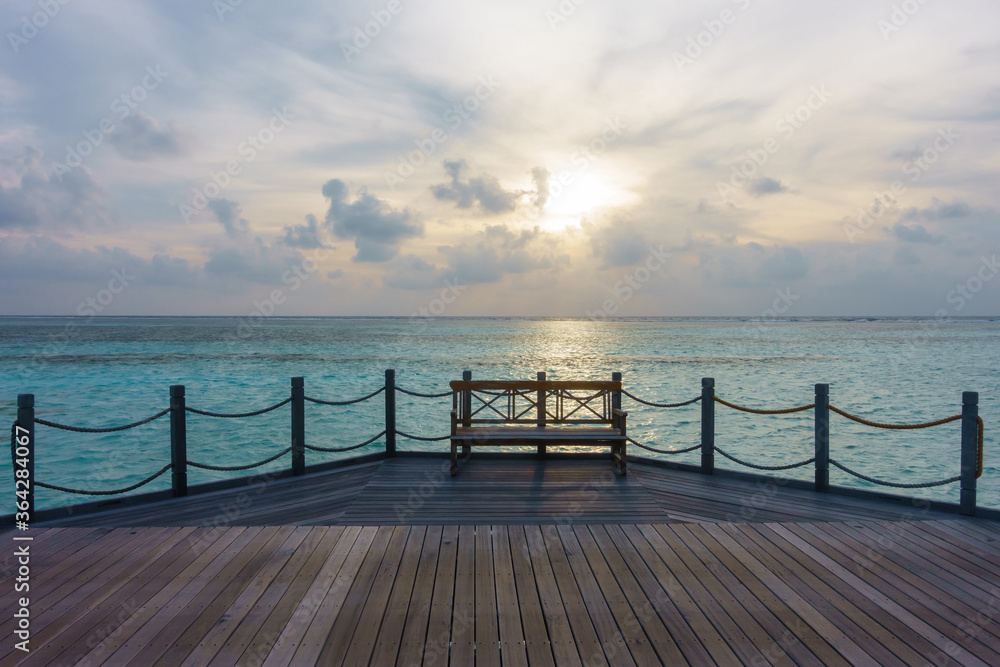 Fototapeta premium Wooden bench on jetty with sunrise in the morning
