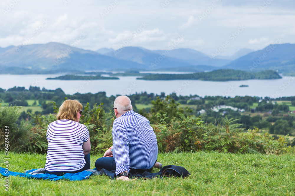 Enderly couple enjoy beautiful panoramic view of Trossachs landscape, Scotland