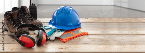 Work safety protection equipment. Industrial protective gear on wooden table, blur site background. photo