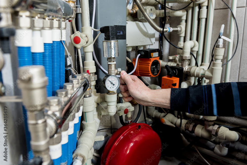 Heating engineer fixing modern heating system in boiler room. Heating engineer fixing modern heating system in boiler room.
