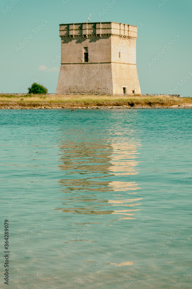 Torre costiera con riflesso della torre sull'acqua del mare.