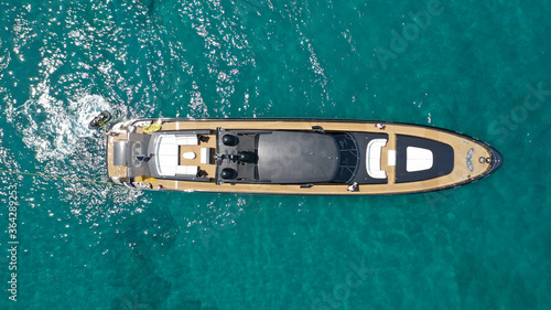 Aerial drone top view photo of large black yacht - boat with wooden deck anchored in tropical exotic paradise with turquoise open sea