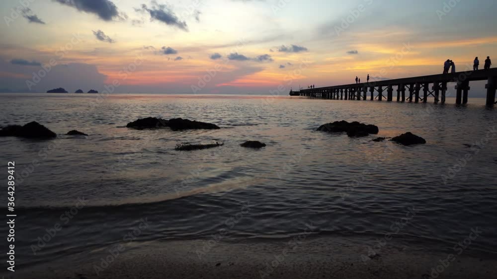 People walk on the pier and watch spectacular sunset over sea People walk on the pier and watch spectacular sunset over sea