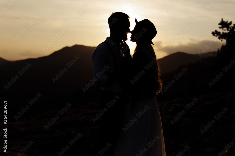 Wedding couple in the sunset. silhouette of groom and bride in mountains.