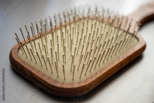 Wooden massage hair brush with iron bristles, macro side view on the shiny grey table.