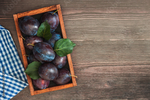 Freash plums in wooden box on wood table top view