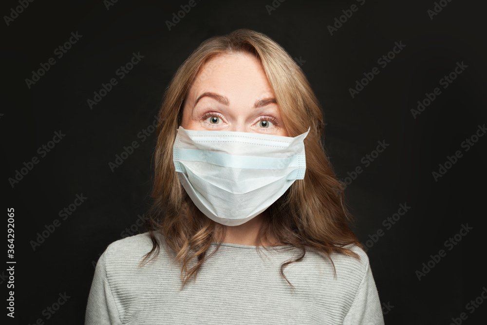 Portrait of casual woman in medical protective face mask on black background Portrait of casual woman in medical protective face mask on black background