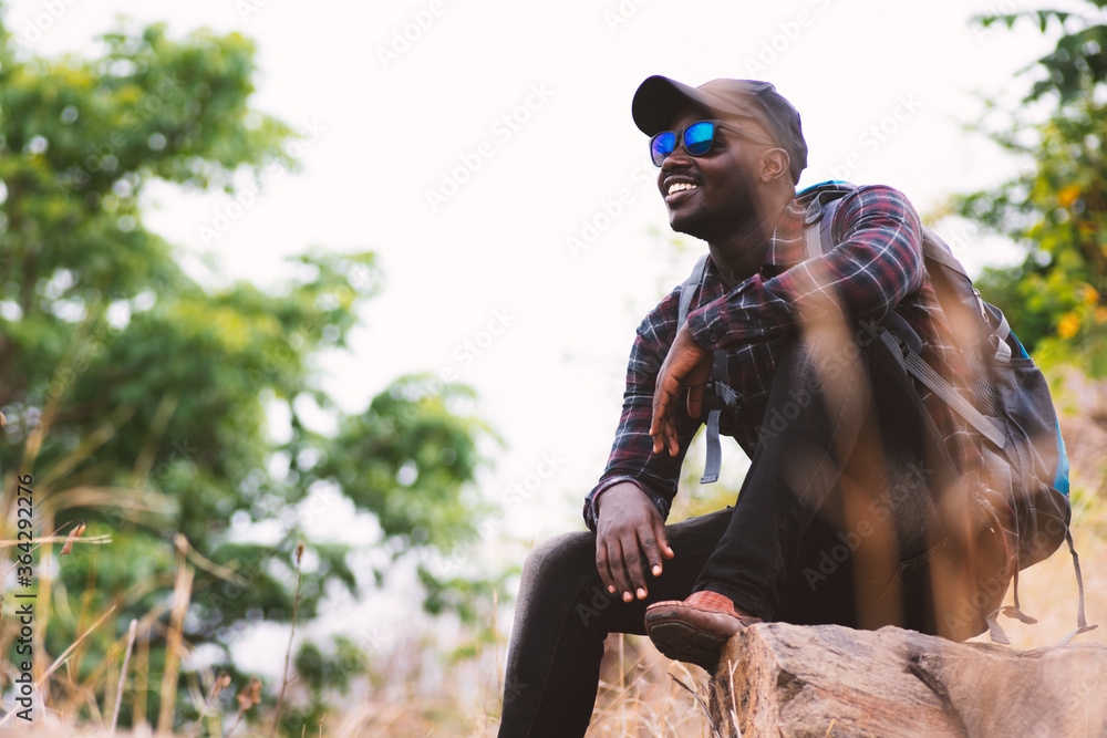 Fototapeta premium African man traveler sitting on the top of moutain with backpack