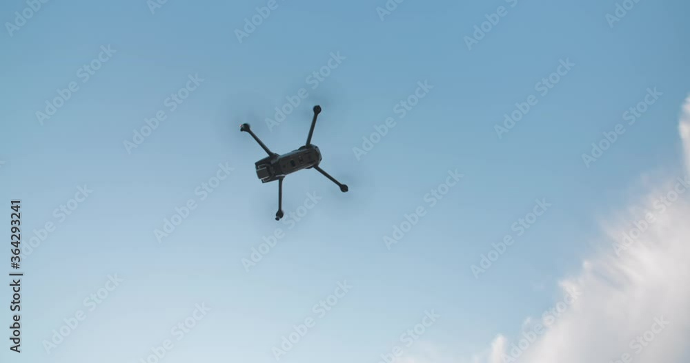 Takeoff drone flies on bright blue sky background. Modern technologies for shooting photos and videos from above. Slow motion shot. Flight overhead Takeoff drone flies on bright blue sky background. Modern technologies for shooting photos and videos from above. Slow motion shot. Flight overhead