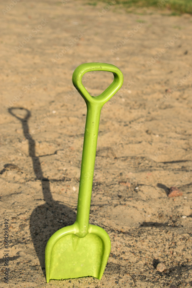 children's green shovel on the background of blurred sand children's green shovel on the background of blurred sand