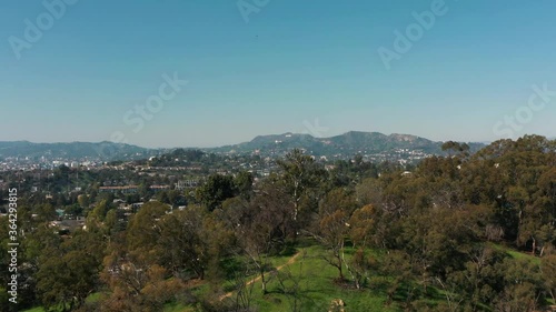 Aerial video flying over a Los Angeles neighborhood toward Beverly Hills with the Hollywood sign in the distance mountains