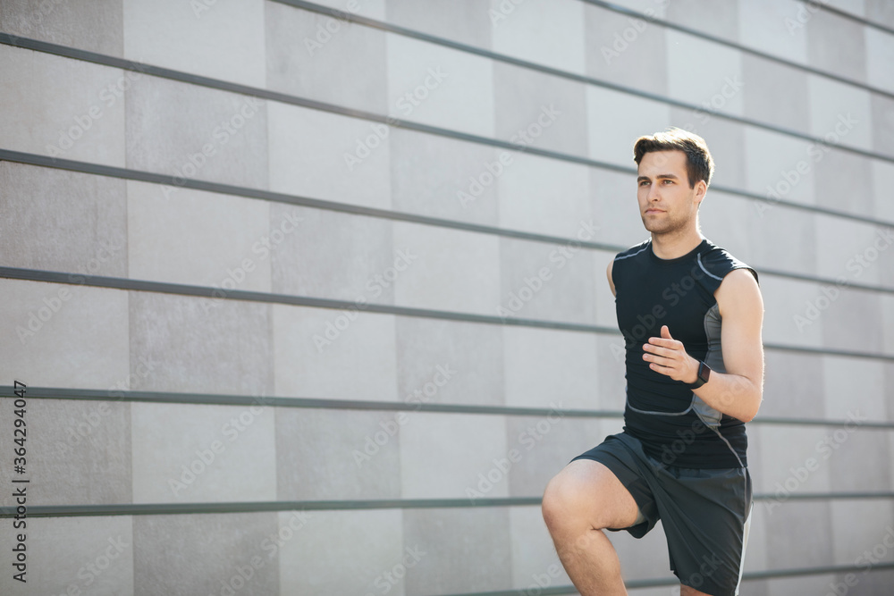 Sports in city. Young guy in sportswear and with fitness tracker running Sports in city. Young guy in sportswear and with fitness tracker running