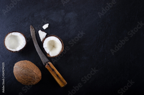 How to crack a coconut. Flat lay with coconuts and old vintage knife on black dark background