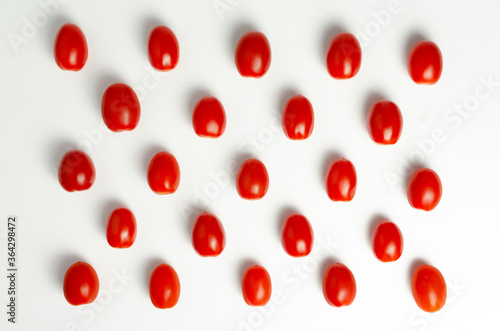 Red cherry tomatoes organised in checkers position on white background