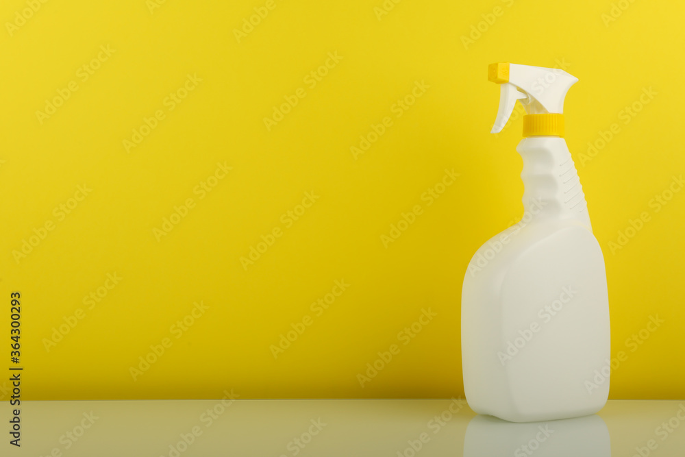 white spray bottle on yellow background with copy space white spray bottle on yellow background with copy space