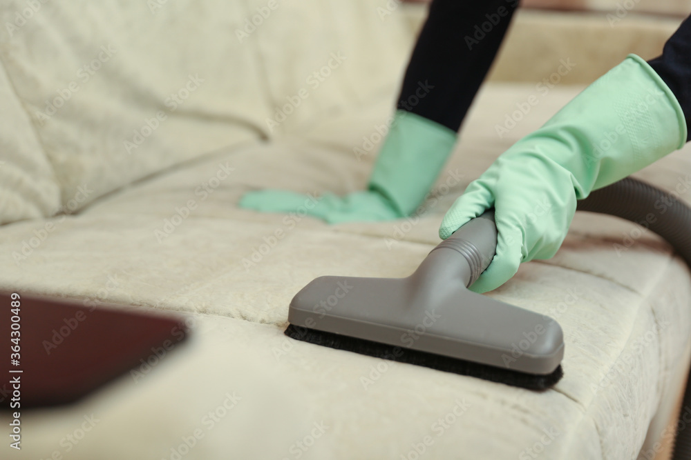 vacuuming furniture by vacuum cleaner close up