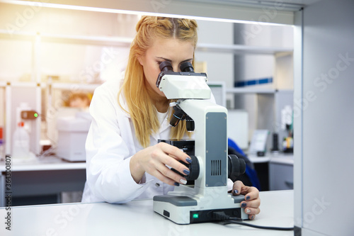young woman laboratory assistant looks at the microscope