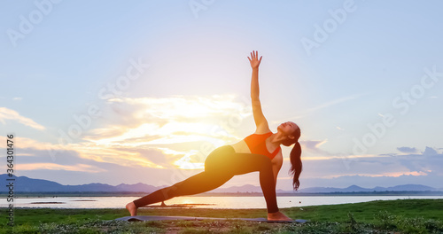 Asian women are exercising with yoga outside near the river in the evening © tuiphotoengineer