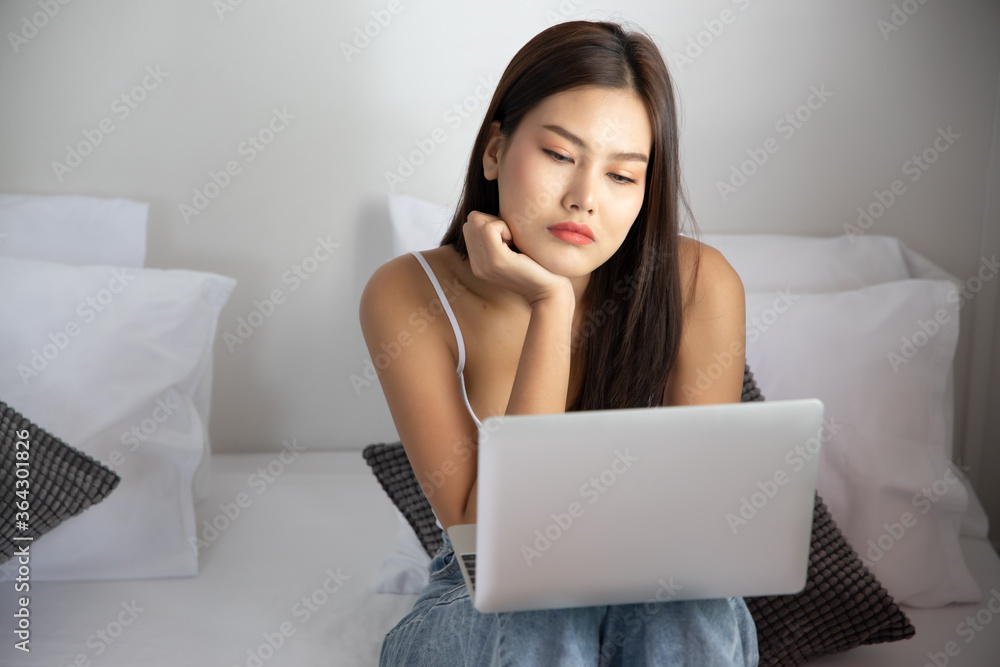 bored unhappy woman working at home with laptop computer; concept of video call, VDO conference, telemedicine videocall, working at home, new normal social distancing precaution bored unhappy woman working at home with laptop computer; concept of video call, VDO conference, telemedicine videocall, working at home, new normal social distancing precaution