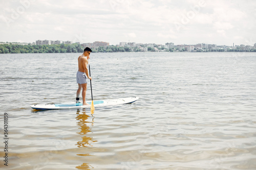 Handsome man with a sup. Surfer on a water