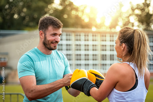 Healthy fitness couple preparing for  boxing training outdoors at sunset while smiling. © Бојана Јаворац