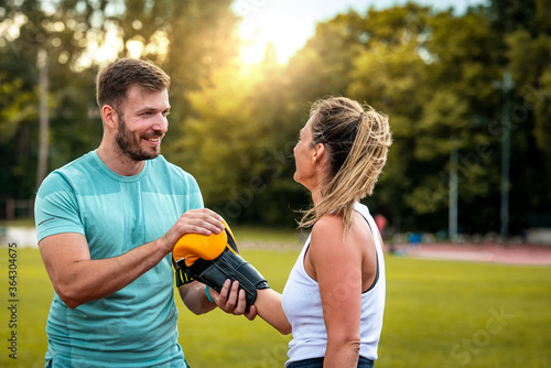 Fototapeta Naklejka Na Ścianę i Meble -  Healthy fitness couple preparing for  boxing training outdoors at sunset while smiling.