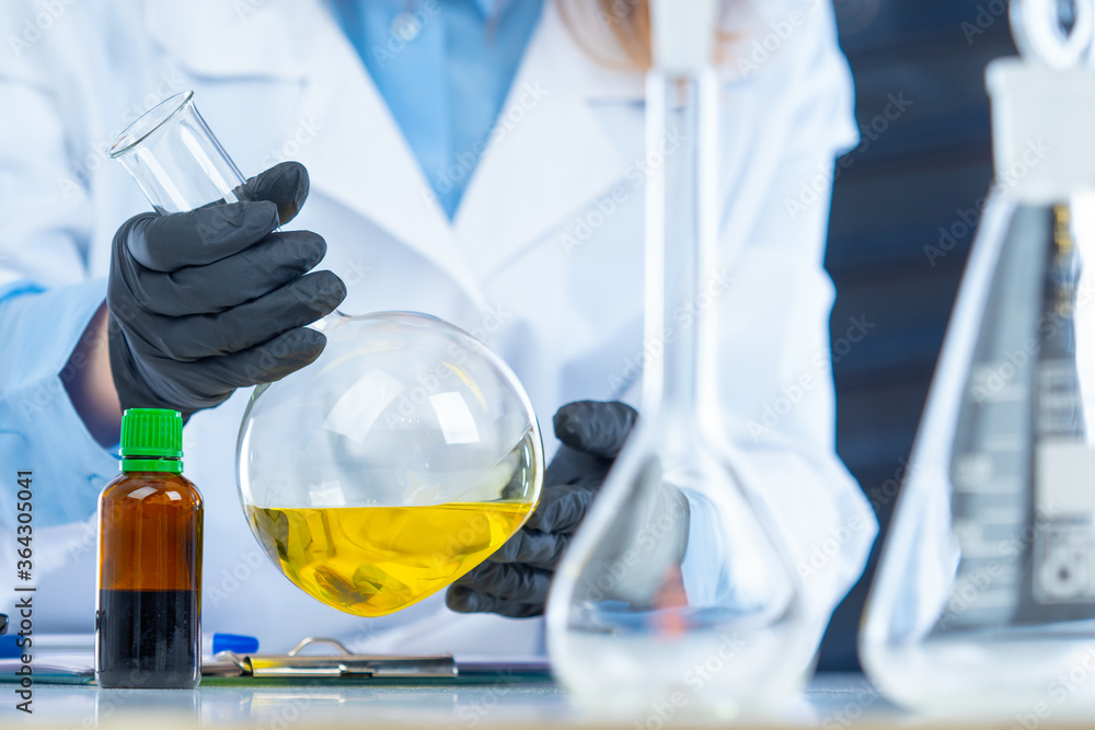 Large test tubes in the hands of a healthcare provider. Chemical lab. Test tube with yellow