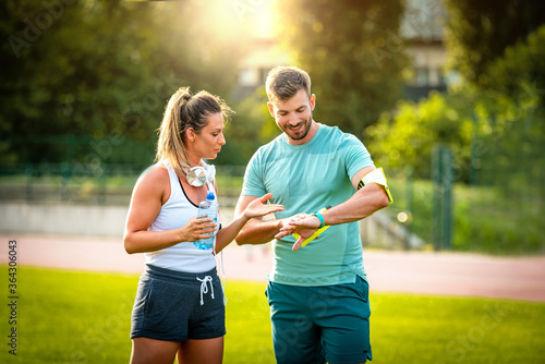 Beautiful athletic couple using sports technology in the park during training