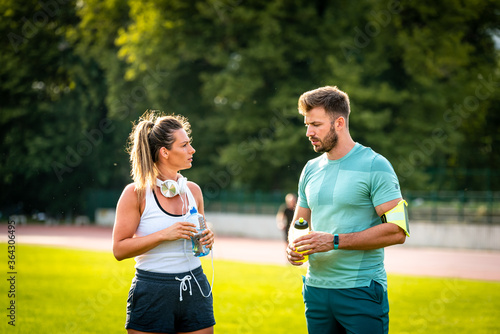 Happy couple communicating after training on water break in park