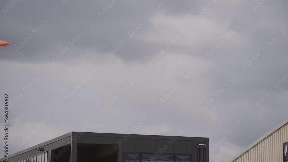 steady shot of an orange paraglider landing oever a building in wanaka.mov steady shot of an orange paraglider landing oever a building in wanaka.mov